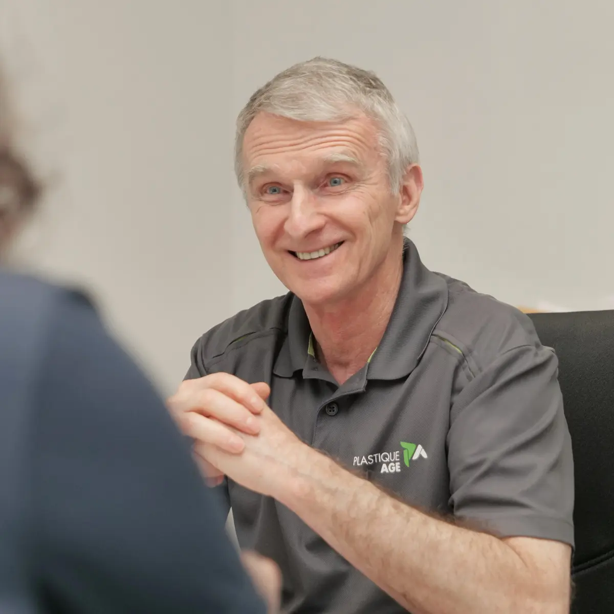 Smiling Plastic Age expert during a client meeting, symbolizing quality commitment